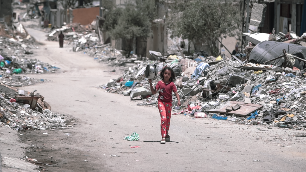 Doppio Colpo alla verità: reporter uccisi e influencer in tour a Gaza Una bambina cammina a Gaza alla ricerca di cibo